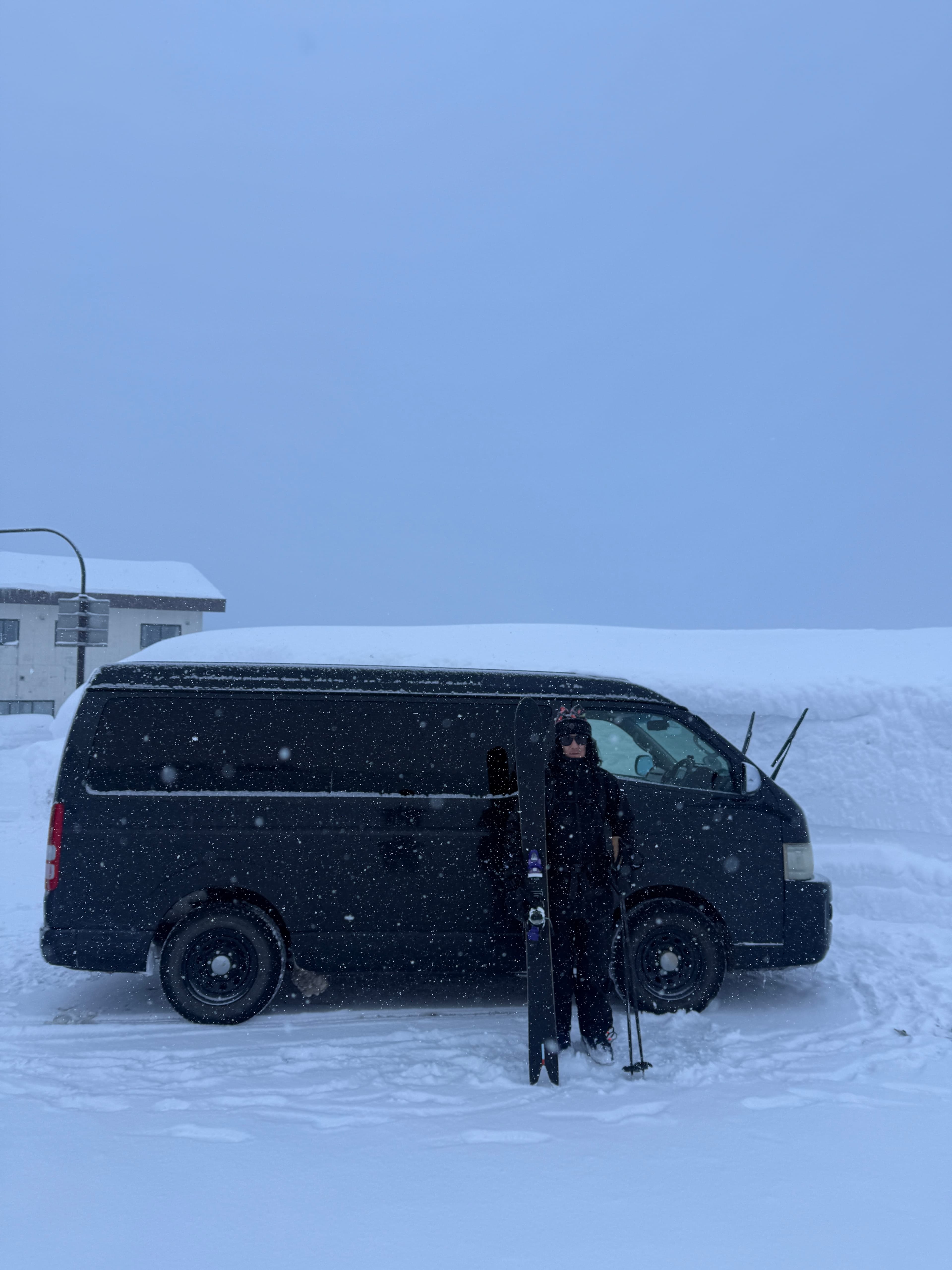 Ryota with skis by the Raven Outdoors van in Furano